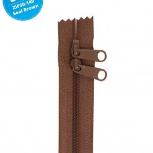 May include: A 30-inch double slide handbag zipper in seal brown. The zipper has two pull tabs with a metal ring.