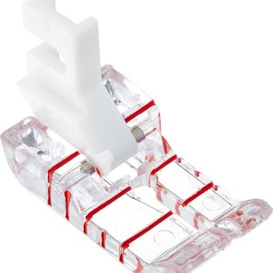 May include: A clear plastic sewing machine foot with red lines and a white plastic attachment. The foot is designed for sewing straight seams.