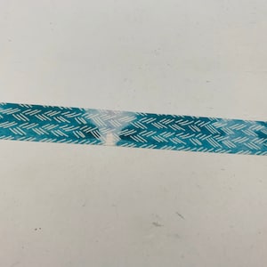 May include: A roll of decorative washi tape featuring a blue and white geometric pattern. The tape has a watercolor-like effect, with a textured appearance. Ideal for scrapbooking, crafts, and adding a decorative touch to various projects.