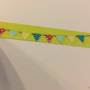 May include: A lime green decorative ribbon with a repeating pattern of small, colorful pennant flags. The flags are in various colors and patterns, including stripes and polka dots, and are strung along a black line.