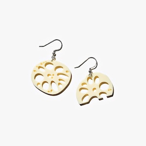 May include: A pair of cream-coloured earrings shaped like lotus root slices. The earrings have a delicate, intricate design and are suspended from silver hooks.