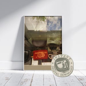 May include: A framed display of various accessories, including a red pouch with a camera design, sunglasses, and a dark leather bag. The image is set against a white wall and a wooden floor, with a "DIGITAL DOWNLOAD" sticker in the foreground.
