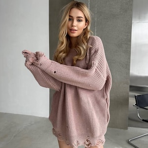 Puede incluir: Un jersey oversize rosa empolvado con dobladillo y mangas desgastadas. El jersey tiene un cuello redondo y un ajuste holgado y cómodo. El tejido de punto es de color liso, perfecto para combinar o llevar solo.