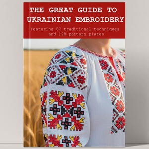 Könnte beinhalten: Ein Buch mit dem Titel "THE GREAT GUIDE TO UKRAINIAN EMBROIDERY" mit rotem und weißem Text. Das Cover zeigt eine weiße Bluse mit aufwendiger roter, schwarzer und gelber Stickerei auf den Ärmeln. Das Buch verspricht 82 traditionelle Techniken und 128 Musterplatten.