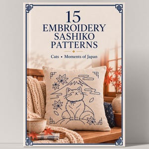 以下が含まれることがあります： 「15 EMBROIDERY SASHIKO PATTERNS Cats • Moments of Japan」というタイトルのブックカバー。表紙には、猫、カエデの葉、山が濃い青色の刺繍で描かれたベージュのクッションが写っており、全体が濃い青色の装飾的な枠で囲まれています。