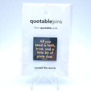 May include: A square pin with the text "All you need is faith, trust, and a little bit of pixie dust." The pin is black with colorful text and is attached to a white card that reads "quotable pins" and "spread the words."