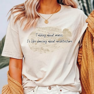 May include: A white t-shirt with a vintage-style graphic print that reads "Talking about music, is like dancing about architecture."