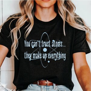May include: Black t-shirt with a blue atom graphic and the text "You can't trust atoms... they make up everything".