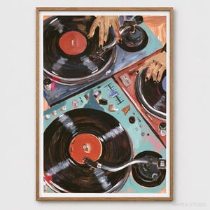 May include: A framed art print depicting two turntables with black vinyl records and orange center labels. The turntables are colored in shades of light blue and red, with visible control knobs and tonearms. The artwork features a painterly style.
