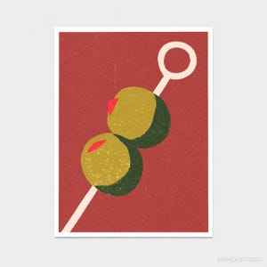May include: A graphic art print on a deep red background featuring two green olives with small red pimentos skewered on a light-coloured cocktail pick. The pick has a circular loop at the top end. The text MAREA STUDIO is printed in the bottom right corner.