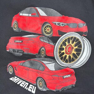 Peut inclure: Un t-shirt noir avec un motif de voiture rouge. La voiture est repr&eacute;sent&eacute;e sous diff&eacute;rents angles, notamment de face, de dos et de c&ocirc;t&eacute;. La voiture a des roues noires avec des accents dor&eacute;s. Le texte "DRVN" et "DRIVEN.EU" est imprim&eacute; sur le t-shirt.