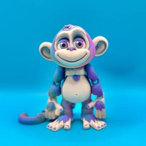 May include: A whimsical, cartoon-style monkey figurine in shades of blue, purple, and cream. The monkey has a cheerful expression with a wide smile and large, expressive eyes. The background is a solid, bright blue.