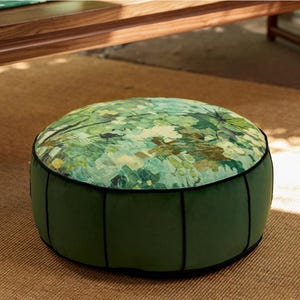 May include: A round green velvet ottoman with black piping and a green and white floral print on the top.