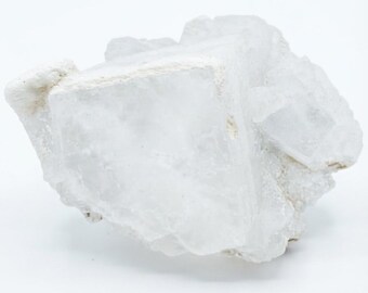 May include: A raw, translucent white mineral specimen with a distinct cubic crystalline structure. The surface features a mix of smooth, flat geometric planes and rough, jagged edges, showcasing a natural, unpolished, and opaque white texture.