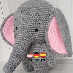 Może przedstawiać: Szary szydełkowy słoń z różowymi uszami. Słoń ma czarne oczy i długi szary trąbę.