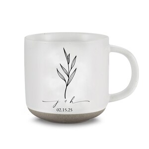 May include: White ceramic mug with a gray base and handle. The mug features a black botanical illustration and the inscription "j + h" with the date "02.15.25".