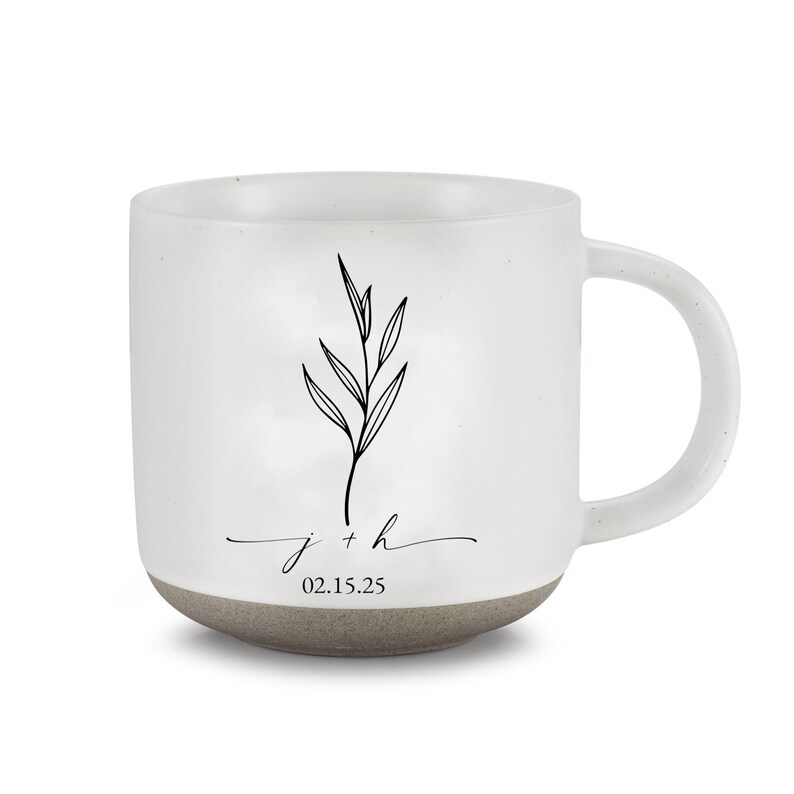 May include: White ceramic mug with a gray base and handle. The mug features a black botanical illustration and the inscription "j + h" with the date "02.15.25".