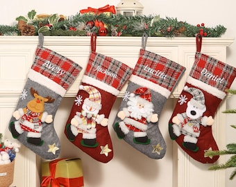 May include: Four Christmas stockings with personalized names: Avery, Jackson, Lucilla, and Daniel. Each stocking features a plaid cuff, a gray or red body, and a festive character like a reindeer, snowman, Santa, or bear. A star and snowflake are also included.