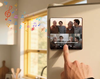 May include: A rectangular, black digital device displaying a photo of four men, with the text "The Man He Sees in Me." Colorful musical notes emanate from the device. The device is attached to a refrigerator.