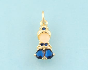 Puede incluir: Encanto de oro con un diseño de muñeca de esmalte azul y blanco. La muñeca tiene una corona azul y un vestido azul con acentos de gemas azules.