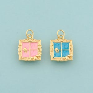 Könnte beinhalten: Zwei goldfarbene Fensteranhänger, einer rosa und einer blau, mit einem Gabel- und Messer-Design. Die Anhänger haben eine quadratische Form mit einem dekorativen Rand und einer kleinen Schlaufe oben.