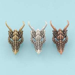 May include: Three dragon head charms in gold, silver, and copper finishes. Each charm features a detailed dragon head with horns, scales, and eyes.