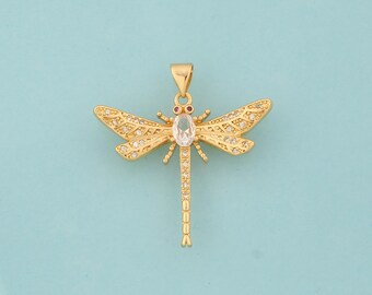 May include: Gold-tone dragonfly pendant with clear and red gemstones. The dragonfly has detailed wings and a long, slender body.