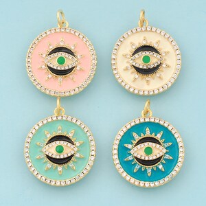 May include: Four gold-tone pendants with a round, enamel-filled design. Each pendant features a black and white evil eye with a green center surrounded by a circle of rhinestones. The pendants are available in four colors: pink, white, turquoise, and light green.