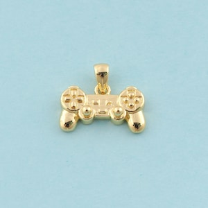 May include: A gold-colored pendant shaped like a video game controller. The pendant has a detailed design with buttons and a directional pad.