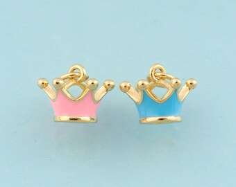 May include: Two gold-colored crown charms with enamel accents. One charm is pink and the other is blue.