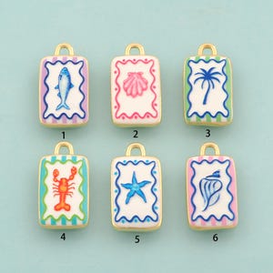 May include: Six rectangular gold-tone metal charms with white enamel centers, each featuring a unique coastal motif: a blue fish, pink shell, blue palm tree, orange lobster, blue starfish, and blue seashell, all framed by colorful striped borders.
