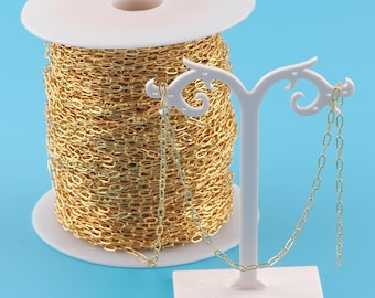 May include: A spool of gold-colored chain, wound around a white plastic spool. The chain is displayed on a white stand, showing the length and size of the chain links.