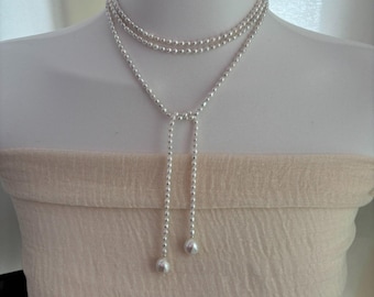 May include: A silver pearl necklace with a long, dangling pearl at the end of each strand.