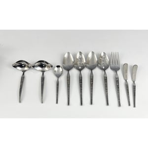 May include: A set of ten silver-toned utensils, including two ladles, a serving spoon, a slotted spoon, a fork, and four butter knives. The utensils have a decorative pattern on the handles.