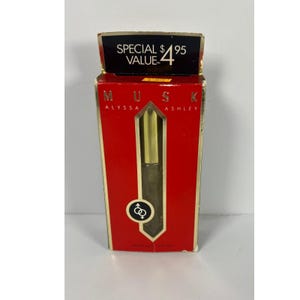 May include: A red box of Alyssa Ashley Musk spray mist. The box has gold trim and the words "MUSK" and "ALYSSA ASHLEY" printed on it. The box also has a gold-colored perfume bottle inside.