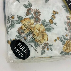 May include: A full-size fitted bottom sheet with a floral print in shades of yellow, brown, and white. The sheet is made of 65% polyester and 35% cotton and is designed for a 54 x 76 inch mattress.
