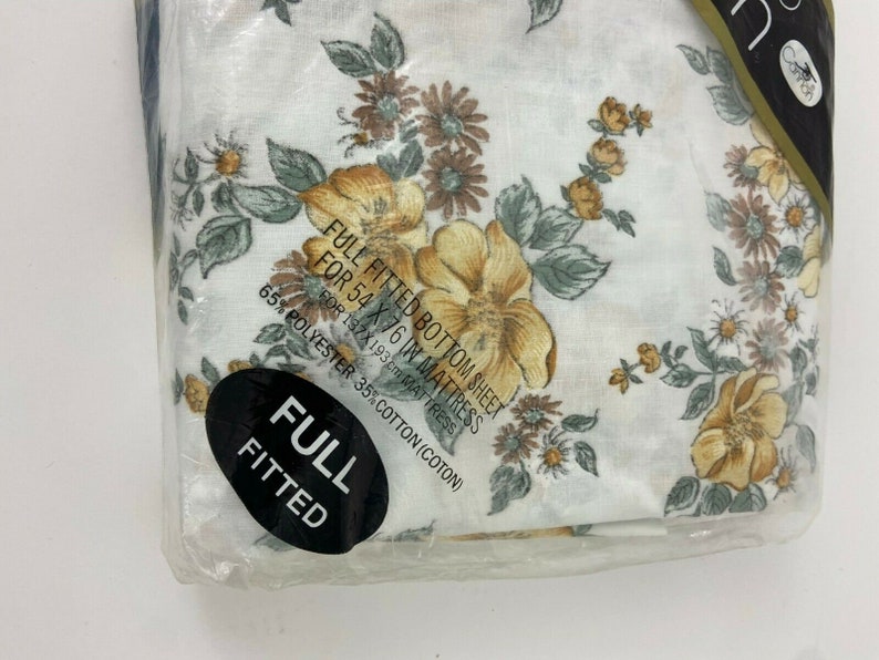 May include: A full-size fitted bottom sheet with a floral print in shades of yellow, brown, and white. The sheet is made of 65% polyester and 35% cotton and is designed for a 54 x 76 inch mattress.