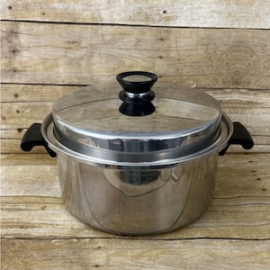 May include: Stainless steel cooking pot with a lid and black handles. The pot has a shiny, reflective surface and a black knob on the lid. The pot is designed for cooking and food preparation.