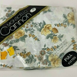 May include: A white fitted sheet with a floral pattern in shades of yellow, brown, and green. The sheet is packaged in plastic and labeled "FULL FITTED" for a 54 x 76 inch mattress. The label also states "MONTICELLO Cannon" and "65% POLYESTER 36% COTTON (COTON)".