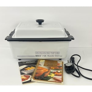 May include: A white NESCO 4 Qt. Roaster Oven with a black handle and lid. The oven has a black trim and a control dial. Two cookbooks are in front of the oven.