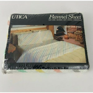 May include: A package of Utica brand flannel sheets in a candy cane stripe pattern. The package shows a bed with a white and pastel striped flannel sheet and two matching pillowcases.