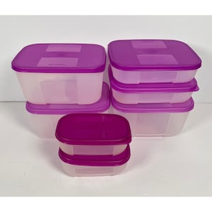 May include: A set of six rectangular food storage containers with translucent white bases and solid purple lids. The containers vary in size and are arranged in a tiered formation, featuring smooth plastic surfaces and secure, snap-on style lids.