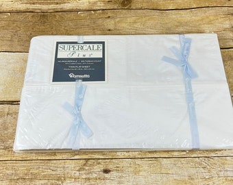 May include: A white twin flat sheet in a plastic package with a blue ribbon. The package has a label that reads "Supercale Plus" with the text "100% Egyptian Cotton, 200 Thread Count" and "Wamsutta" printed on it.