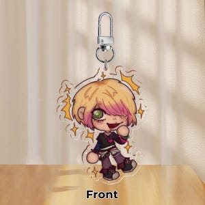 May include: A clear acrylic charm depicting a cartoon character with blonde hair, pink highlights, and green eyes. The character is winking and wearing a black top with purple trousers. The charm has a silver keychain and the word "Front" is printed at the bottom.