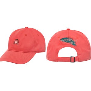 Puede incluir: Gorra de béisbol de color coral con un cangrejo bordado en la parte delantera. La parte trasera de la gorra presenta el texto "SOUTH FLORIDA CLOTHIERS" en color turquesa. Correa ajustable para un ajuste cómodo.