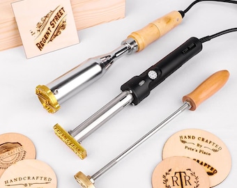 May include: Three metal branding irons with wooden handles and electrical cords, alongside several circular wooden discs featuring burned designs including "Regent Street," "Handcrafted by Lisa Meccia," and "Hand Crafted by Pete's Place."