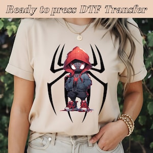 May include: A beige t-shirt with a black spider web design and a cartoon image of Spider-Man in a red hoodie and black suit. The text "Ready to press DTF Transfer" is at the top of the image.