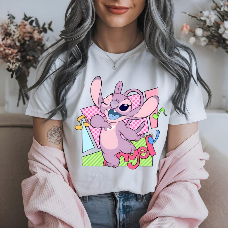 May include: White t-shirt with a cartoon image of Stitch from Lilo & Stitch singing with the word "Angel" in pink letters.
