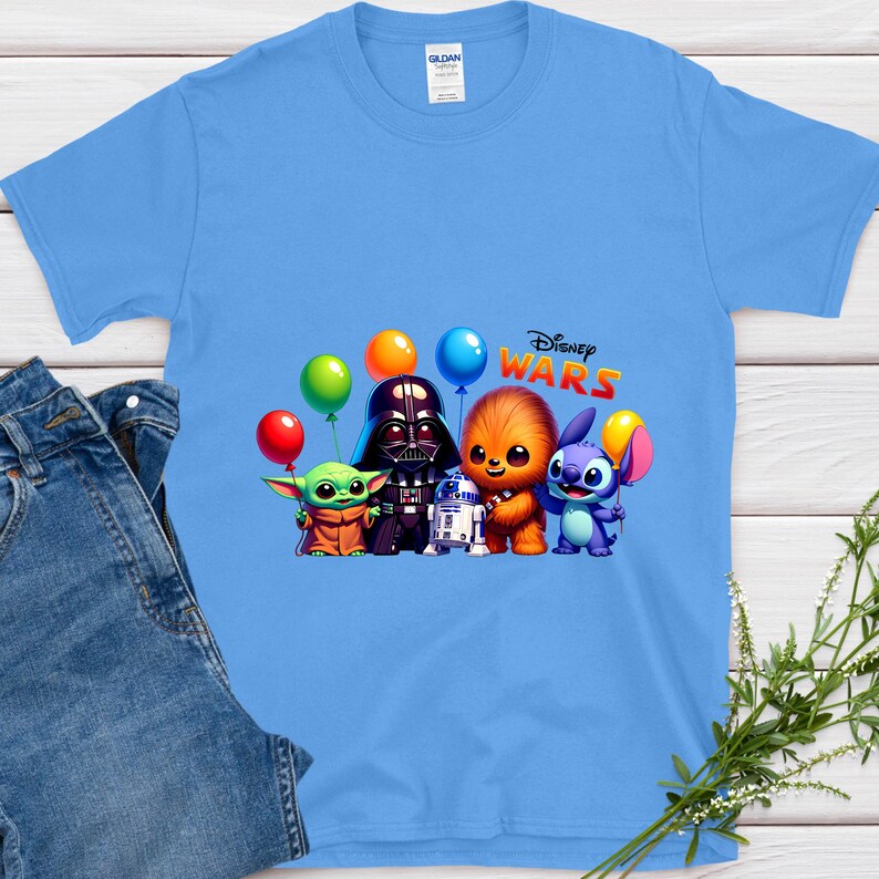 May include: Pale blue t-shirt with a graphic of Star Wars characters, including Darth Vader, Chewbacca, and Grogu, with colourful balloons and the text "Disney Wars". The shirt is made of a soft material.