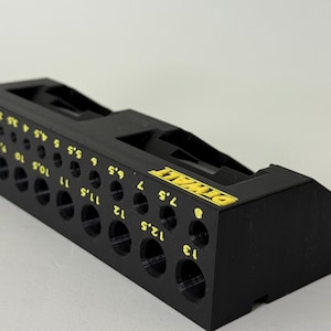 May include: Black drill bit holder with yellow text and hole sizes. The holder has the word "DEWALT" in yellow. Hole sizes are in millimetres, ranging from 1 mm to 13 mm.